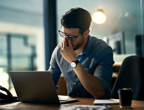 Man met burn-out vermoeid achter laptop