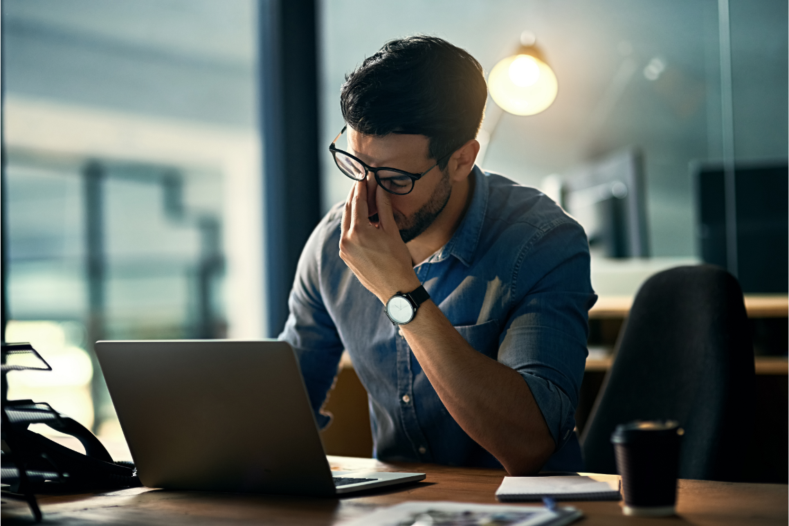 Man met burn-out vermoeid achter laptop